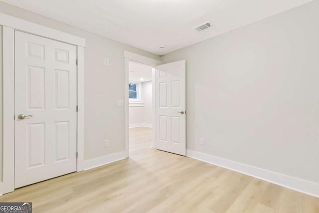 unfurnished bedroom featuring visible vents, light wood-style flooring, and baseboards