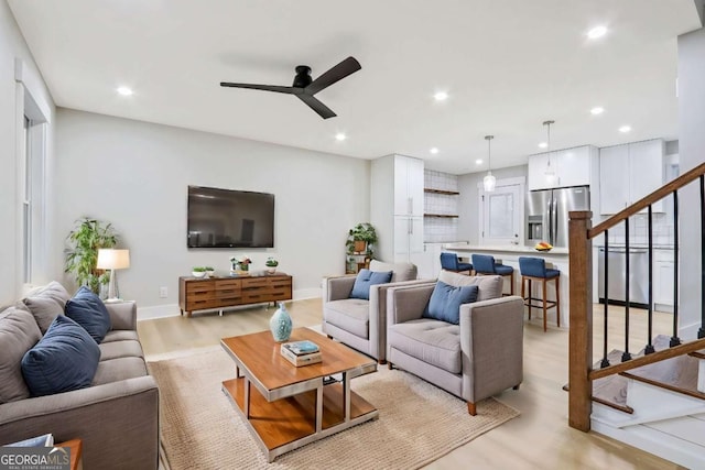 living room featuring ceiling fan, recessed lighting, baseboards, stairs, and light wood-type flooring