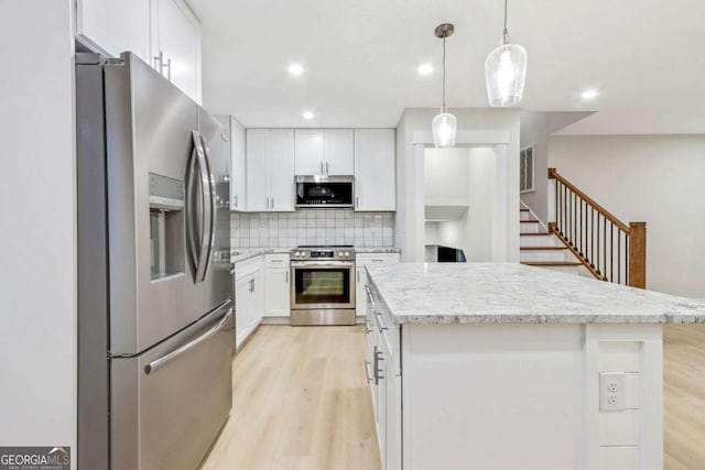 kitchen with appliances with stainless steel finishes, a center island, white cabinets, and decorative backsplash