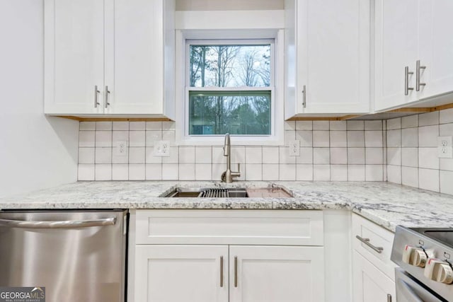 kitchen featuring stainless steel appliances, white cabinets, a sink, and decorative backsplash