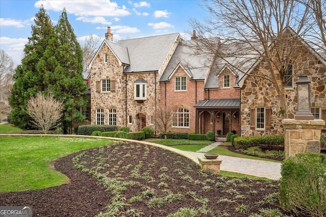 view of front of home with a chimney, a standing seam roof, a high end roof, stone siding, and a front lawn