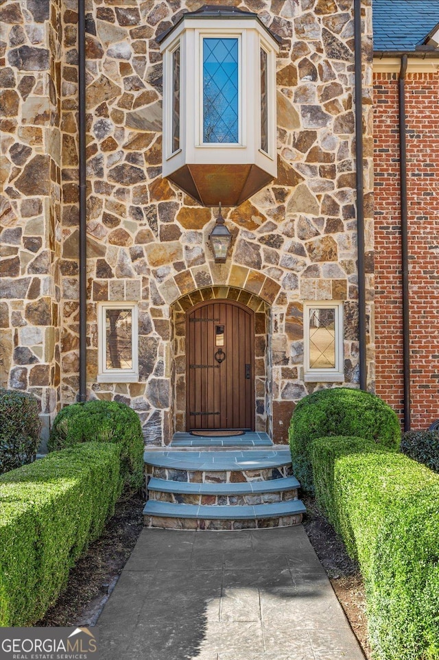 property entrance with stone siding and brick siding