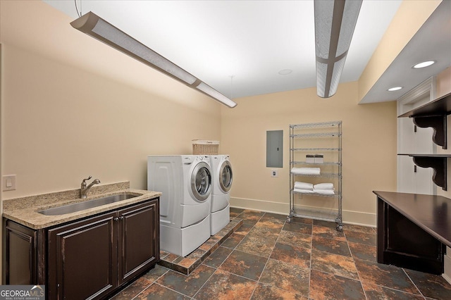 washroom featuring electric panel, baseboards, stone finish flooring, washing machine and dryer, and a sink