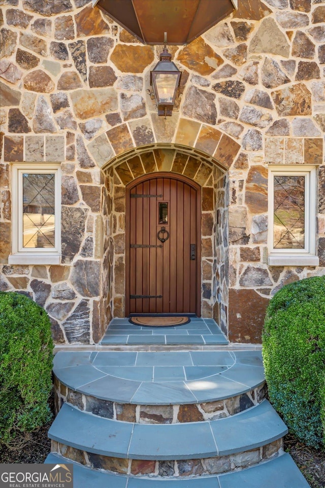 entrance to property featuring stone siding and a fireplace