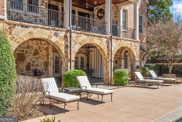 view of patio featuring a balcony, ceiling fan, and french doors