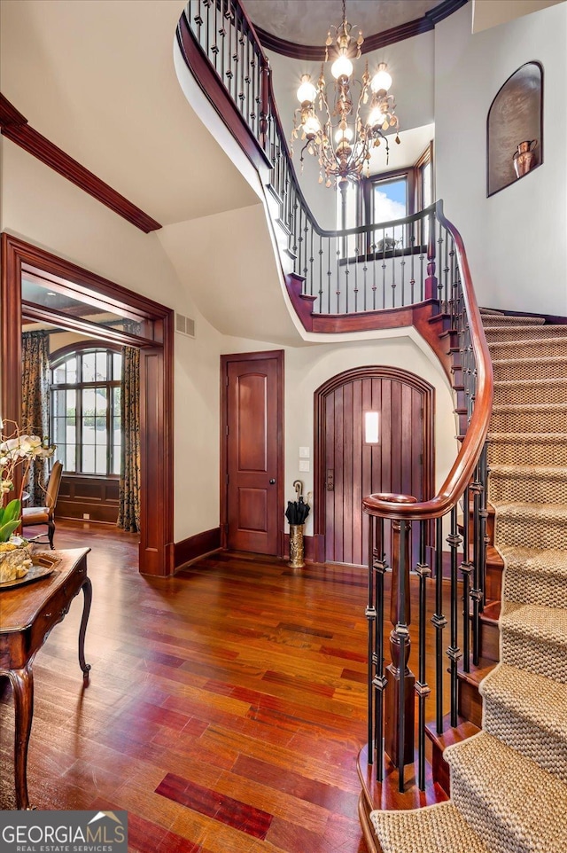 entryway with stairs, wood finished floors, visible vents, and an inviting chandelier