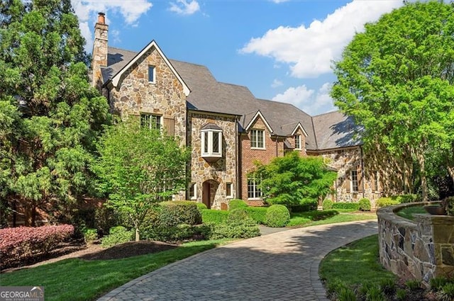 view of front facade featuring stone siding and a chimney