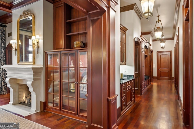 hallway featuring dark wood-type flooring, ornamental molding, and baseboards