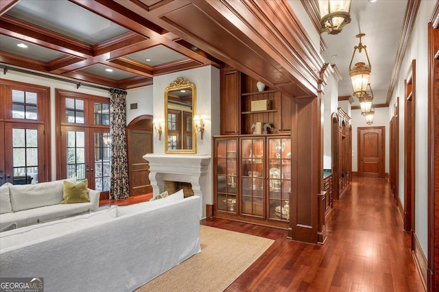 interior space with dark wood-style flooring, a fireplace, coffered ceiling, ornamental molding, and beamed ceiling