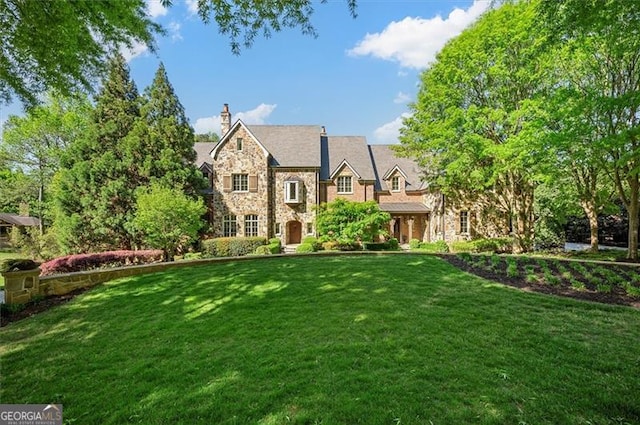 view of front of property with stone siding, a front lawn, and a chimney