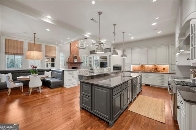 kitchen featuring gray cabinetry, stainless steel stove, a sink, open floor plan, and white cabinetry