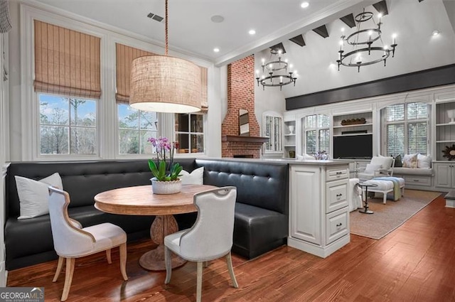 dining area featuring a chandelier, breakfast area, wood finished floors, plenty of natural light, and high vaulted ceiling