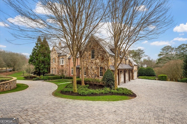 view of front facade with decorative driveway, stone siding, and a garage