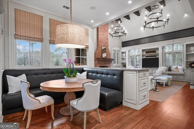 dining room featuring breakfast area, wood finished floors, crown molding, a brick fireplace, and high vaulted ceiling