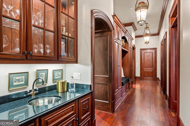 bar with crown molding, dark wood-type flooring, a sink, wet bar, and baseboards