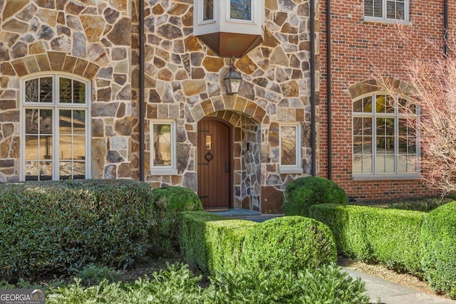 property entrance featuring stone siding and brick siding