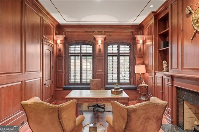 office space featuring a premium fireplace, a decorative wall, and crown molding