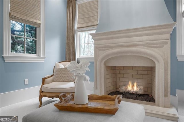 sitting room featuring a lit fireplace, healthy amount of natural light, and carpet floors