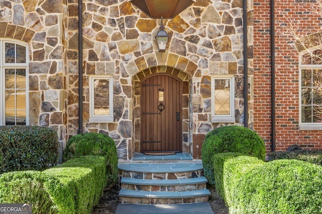 view of exterior entry featuring stone siding and brick siding