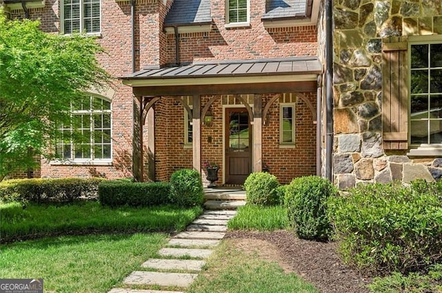 view of exterior entry featuring a standing seam roof and brick siding