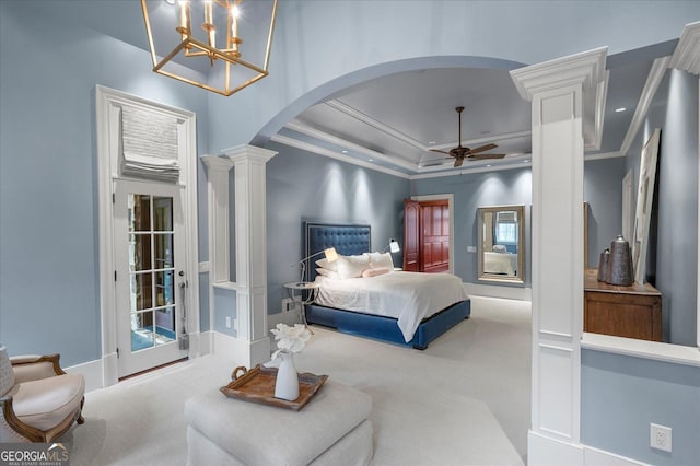 carpeted bedroom with arched walkways, ceiling fan, ornamental molding, a tray ceiling, and ornate columns