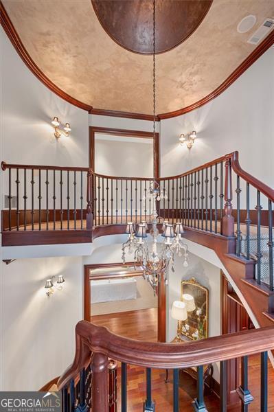 staircase featuring a high ceiling, ornamental molding, and wood finished floors