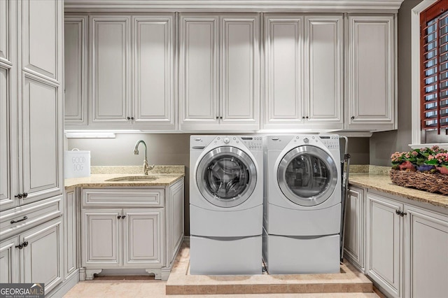 laundry room with cabinet space, washing machine and dryer, light tile patterned floors, and a sink