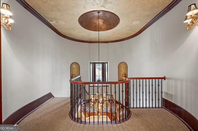 hall with ornamental molding, visible vents, carpet floors, and an upstairs landing