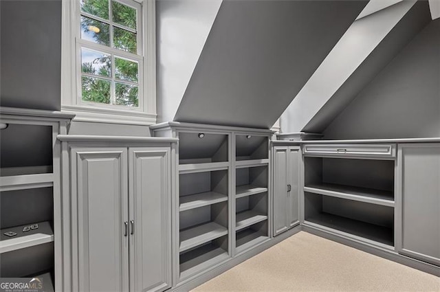 walk in closet with light carpet and lofted ceiling