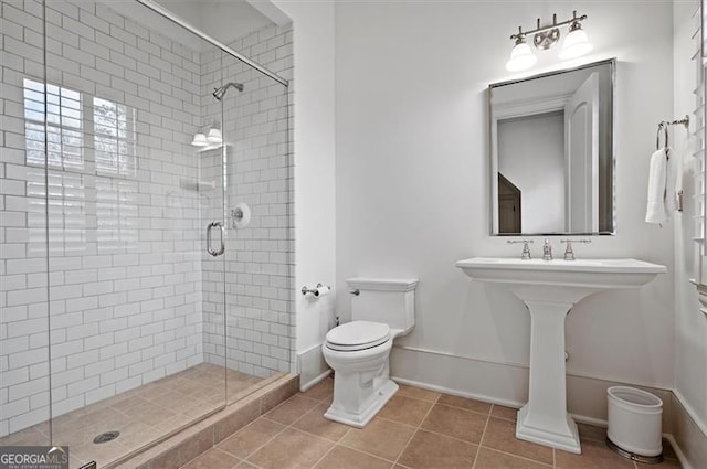 bathroom with toilet, a shower stall, tile patterned floors, and baseboards