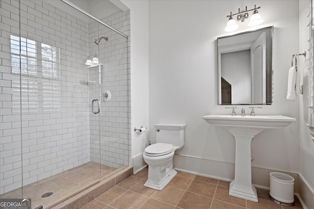 full bath with tile patterned flooring, baseboards, a shower stall, and toilet