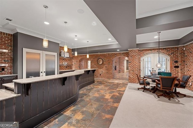 kitchen with french doors, brick wall, crown molding, recessed lighting, and a breakfast bar area