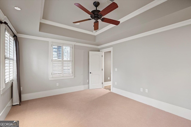 carpeted spare room with a ceiling fan, baseboards, a tray ceiling, and crown molding