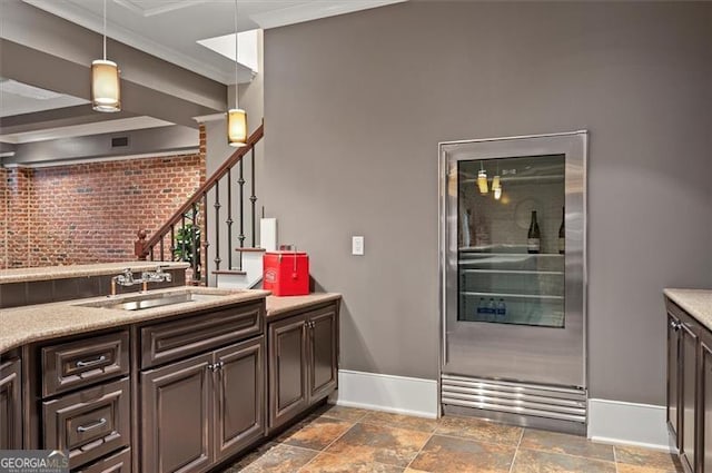 kitchen with refrigerator, baseboards, a sink, ornamental molding, and hanging light fixtures
