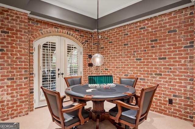 dining space with brick wall, crown molding, and carpet flooring