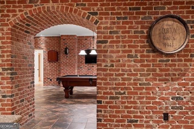 recreation room with pool table and brick wall