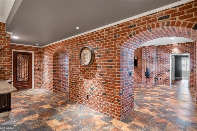 hall featuring brick wall, ornamental molding, recessed lighting, and stone finish floors