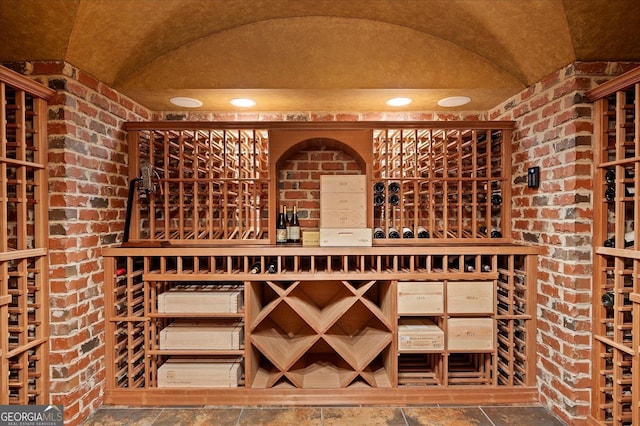 wine area featuring vaulted ceiling and brick wall