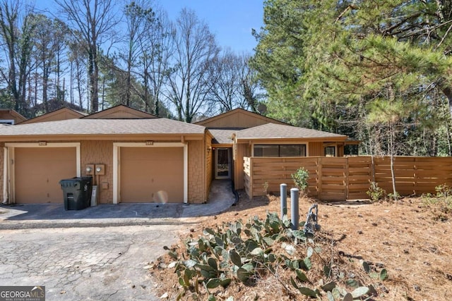 single story home featuring decorative driveway, an attached garage, and fence