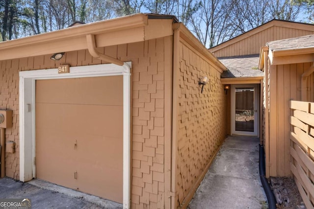 property entrance with a garage and roof with shingles