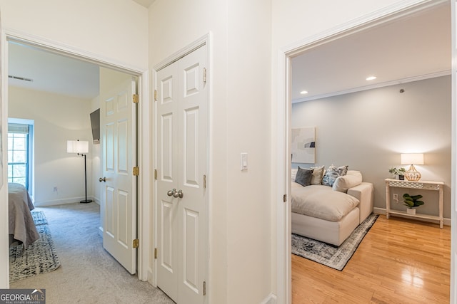 hallway featuring visible vents, baseboards, light wood-style flooring, ornamental molding, and recessed lighting