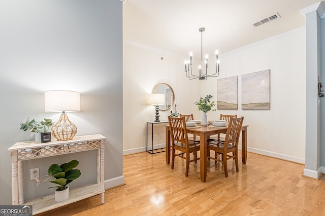 dining space featuring baseboards, visible vents, wood finished floors, and ornamental molding