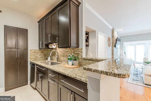 kitchen featuring light stone counters, dark brown cabinetry, a sink, dishwasher, and tasteful backsplash