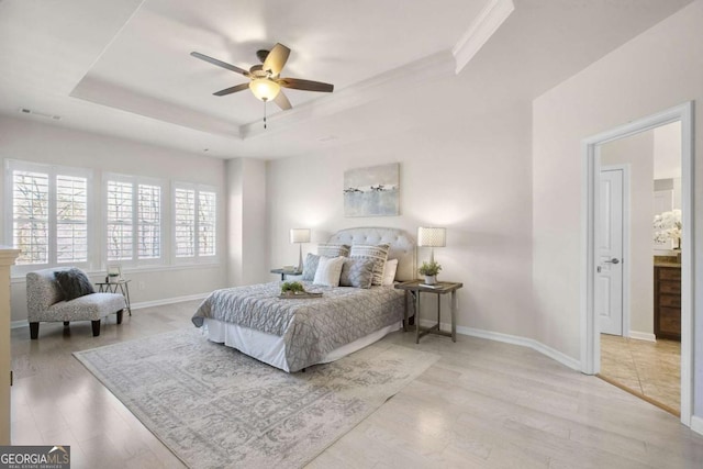 bedroom featuring a tray ceiling, light wood finished floors, visible vents, ceiling fan, and baseboards