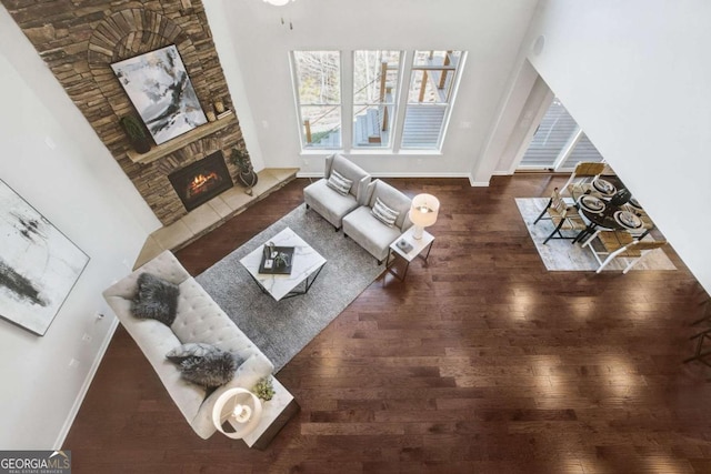 unfurnished living room featuring a stone fireplace, wood finished floors, and baseboards