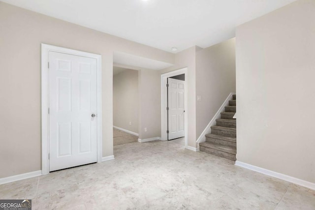 empty room with stairway and baseboards