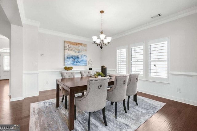 dining room with arched walkways, visible vents, a notable chandelier, and wood finished floors