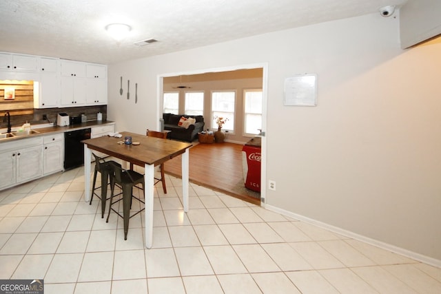 kitchen featuring a sink, light tile patterned floors, visible vents, and dishwasher