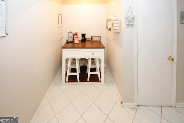 corridor with baseboards and tile patterned floors