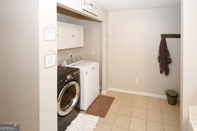 laundry area featuring light tile patterned floors, cabinet space, baseboards, independent washer and dryer, and a textured ceiling